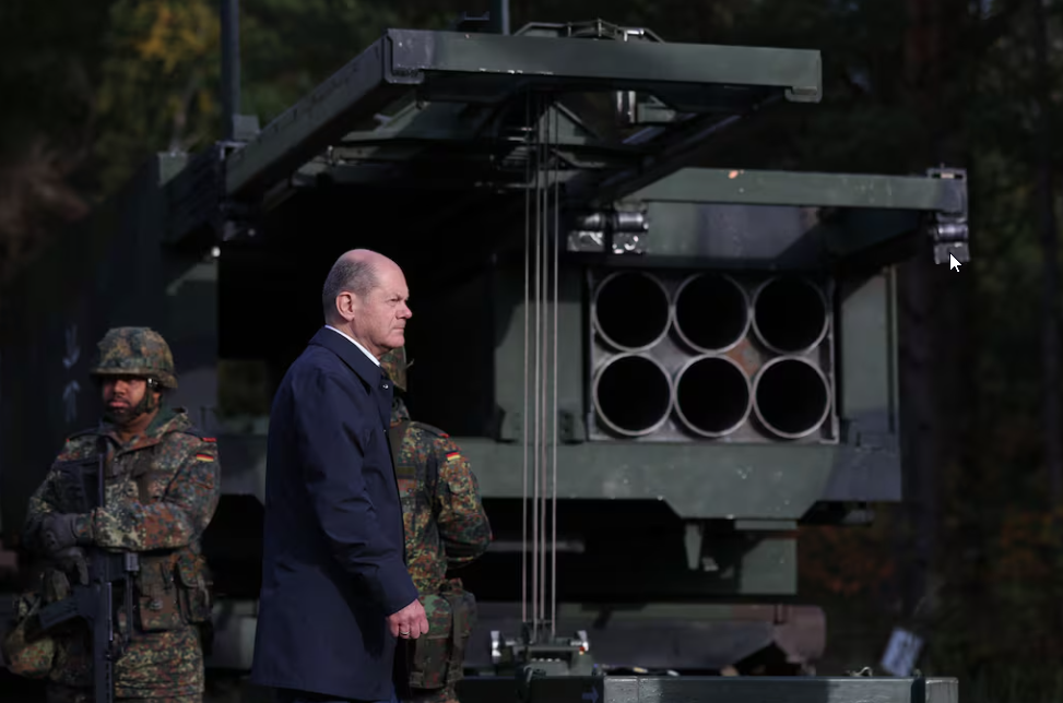 De Duitse Kanselier Olaf Scholz loopt langs het Multiple Launch Rocket System (MARS II). Illustratie: AFP De Duitse bondskanselier Olaf Scholz naast het Multiple Launch Rocket System (MARS II)